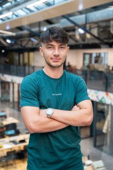 Jeune professionnel debout, bras croisés, dans un espace de coworking lumineux et moderne