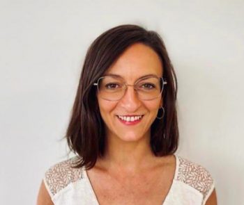 Portrait d'une femme souriante avec lunettes sur fond blanc, photo de profil professionnelle