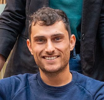Portrait d'un homme souriant en sweat bleu, gros plan en intérieur, lumière naturelle