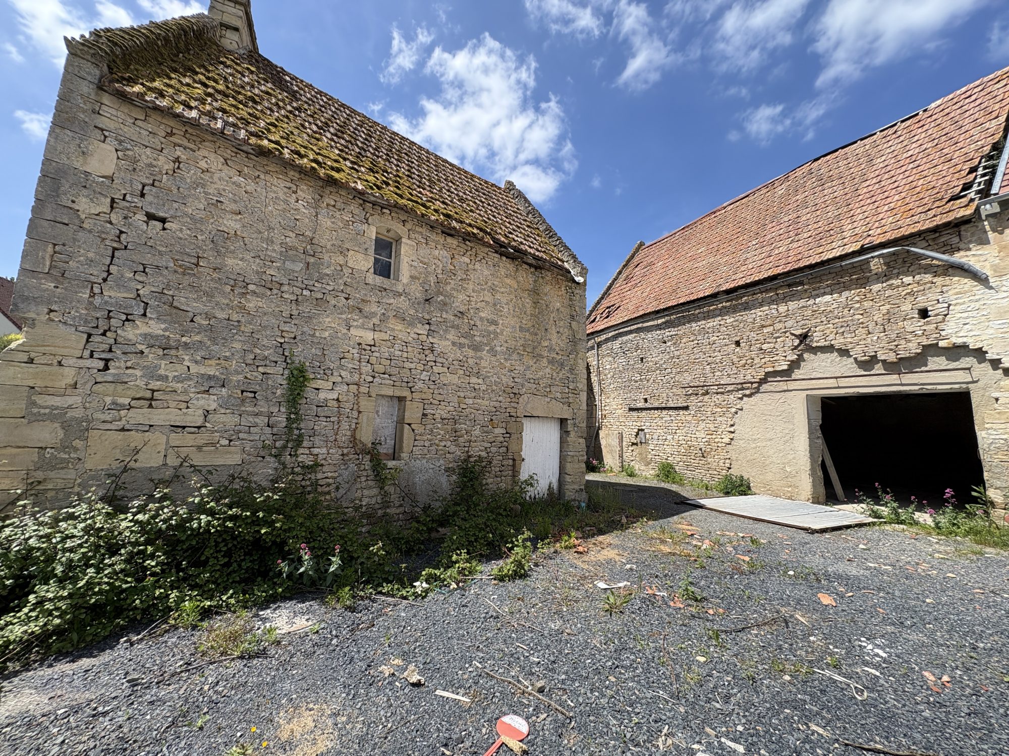 Anciennes granges en pierre aux toits en tuiles dans une cour rurale ensoleillée