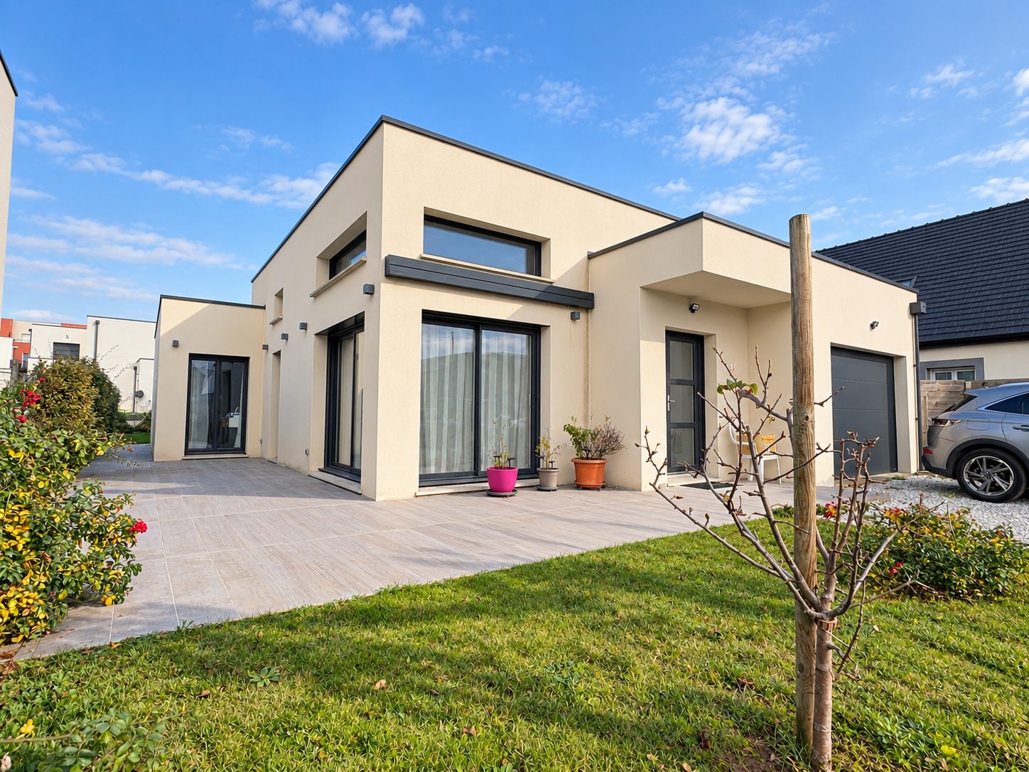 Maison contemporaine à toit plat avec terrasse carrelée, jardin et baies vitrées